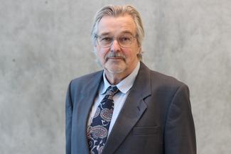 Michael Eso smiling, wearing a grey suit in an airy modern room
